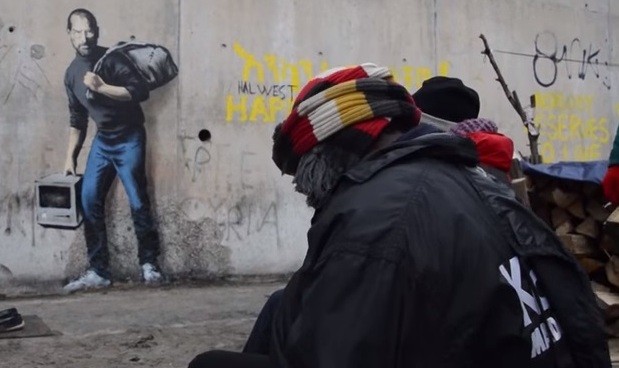 Migrants in a refugee camp in Calais, France see the Steve Jobs graffiti art created by English street artist Banksy.