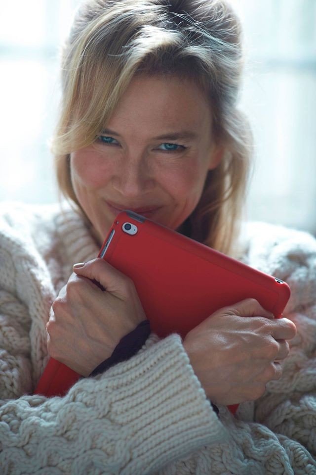 Renée Zellweger smiles while clutching an iPad.