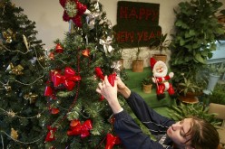 A woman hangs Christmas ornaments on a tree as she celebrates the holidays away from her family.