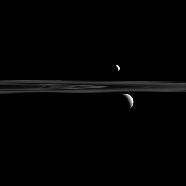 Saturn's rings along with its trio of moons, Rhea, Enceladus and Atlas.