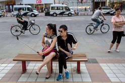 A Chinese couple takes pictures of themselves as they sit at a shopping district in Beijing, China.