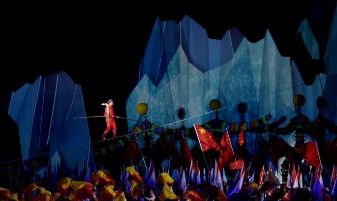 China's famous wire-walking artist Adli (top) carries the torch and walks on a wire during the opening ceremony of the 13th Chinese National Winter Games.