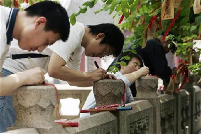Students write wish cards for the upcoming National College Entrance Exam in a Confucius temple in Shanghai, June 5, 2008. 