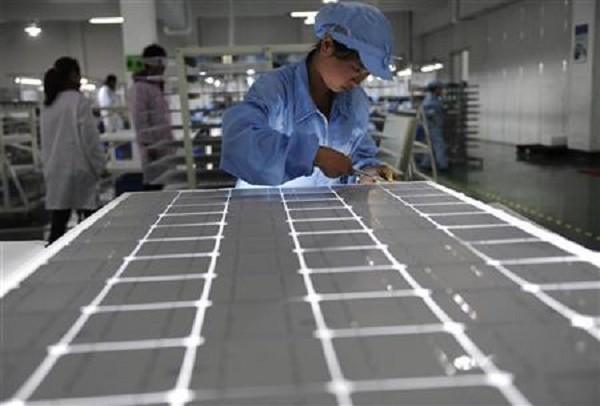 A worker checks products on a solar panel production line at a solar company workshop in Yongkang, Zhejiang Province.