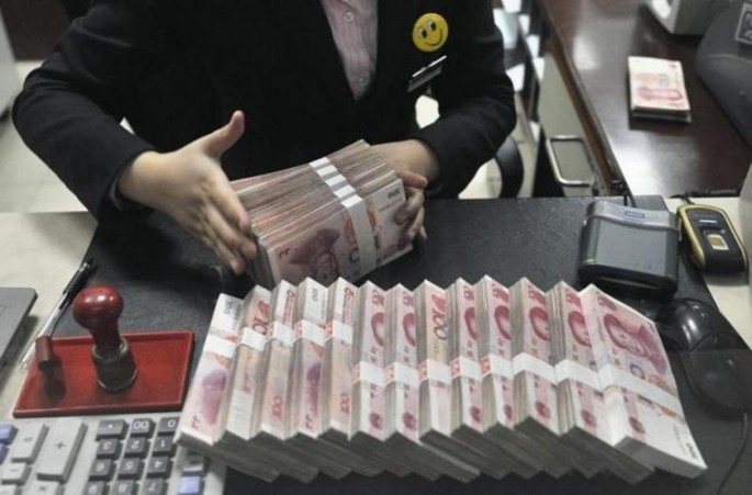 A clerk arranges bundles of 100 Chinese yuan banknotes at a branch of China Merchants Bank in Hefei, Anhui Province, March 17, 2014.