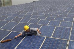 A worker cleans solar panels on the rooftop of a building in Yiwu, Zhejiang Province.