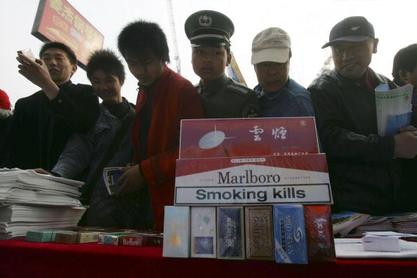 People examine fake cigarettes during a promotional event of World Consumer Rights Day in Beijing, on March 15, 2007. 