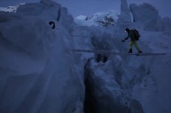 A mountaineer uses a steel ladder as a makeshift bridge to cross a deep crevasse on Mt. Qomolangma, more widely known as Mt. Everest.