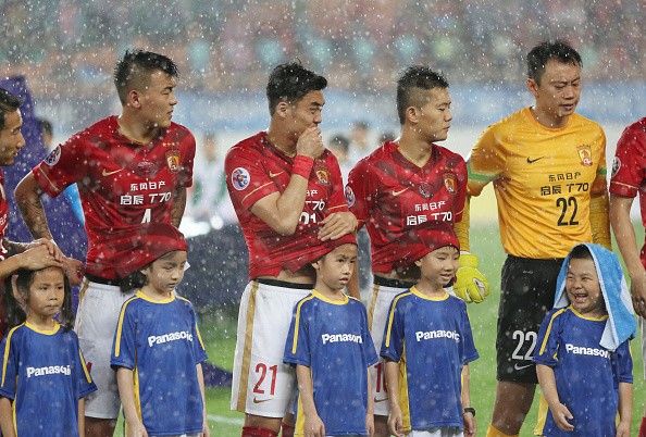 Players of Guangzhou Evergrande use their shirts to protect the ball kids from heavy rain during a match at Tianhe Sports Center in Guangzhou, China, on May 5, 2015.