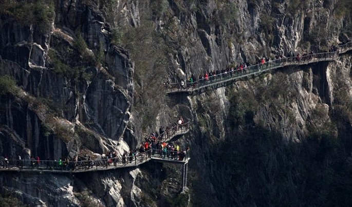 Tourists flock the walkway in Chongqing Qianjiang, apparently not minding much the daunting location and dizzying height.