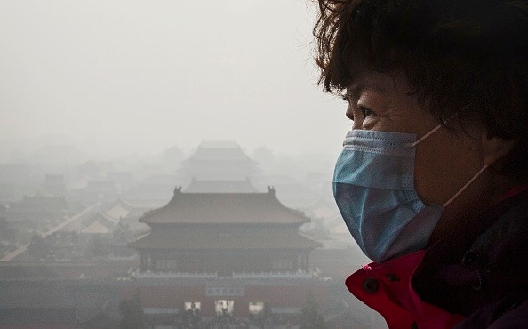 A Chinese woman wears a mask as haze from smog caused by air pollution hangs over the Forbidden City in Beijing, China, on Nov. 15, 2015.