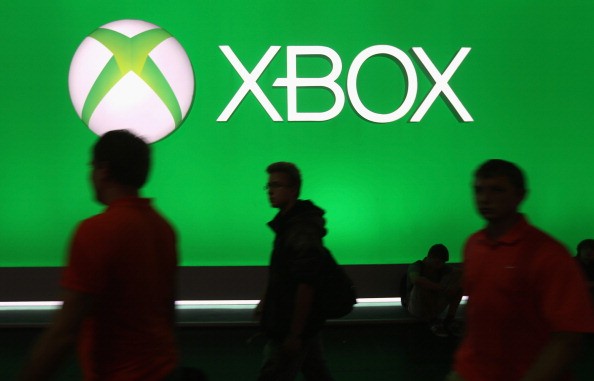 Gaming enthusiasts pass by the XBOX logo at the Gamescom 2013 gaming trade.