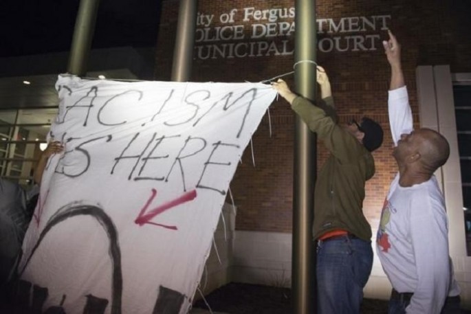 Protesters hang a banner against racism in a police precinct in Ferguson, Missouri.