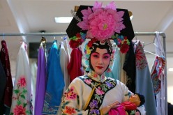 An artist of a Chinese opera troupe poses for a photo in the backstage.