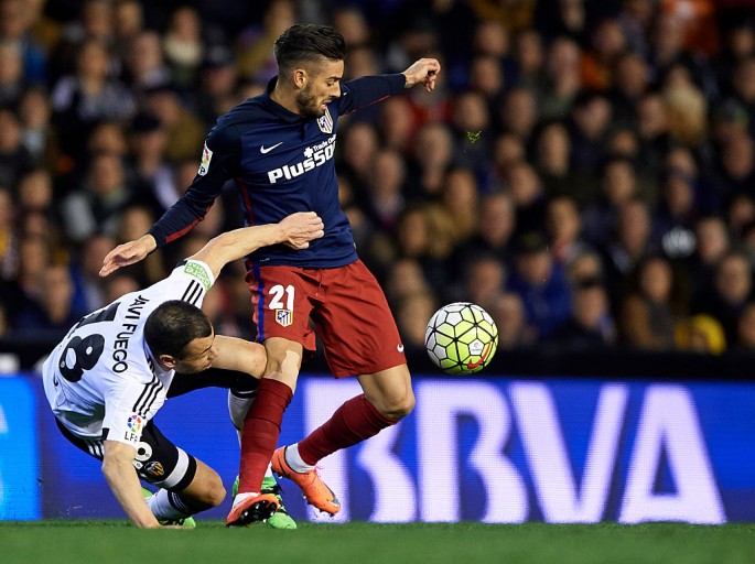 Atletico Madrid winger Yannick Carrasco is tackled by Valencia's Javi Fuego.