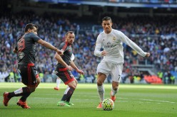 Real Madrid forward Cristiano Ronaldo competes for the ball against two Celta Vigo defenders.