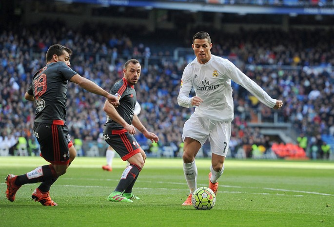 Real Madrid forward Cristiano Ronaldo competes for the ball against two Celta Vigo defenders.