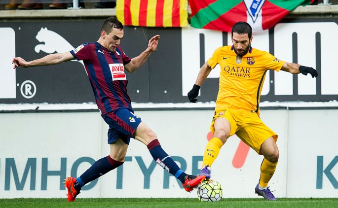 Eibar midfielder Gonzalo Escalante competes for the ball against Barcelona's Arda Turan.