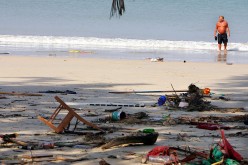 A Swedish tourist wades in the ocean along a garbage strewn and tsunami-struck beach December 27, 2004 in Phuket, Thailand.