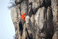 Shaolin kung fu masters practice on a cliff at Songshan Mountain in Dengfeng, Central China's Henan Province, March 17, 2016. 