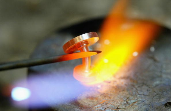  A platinum cufflink is heated up with a torch to repair it.