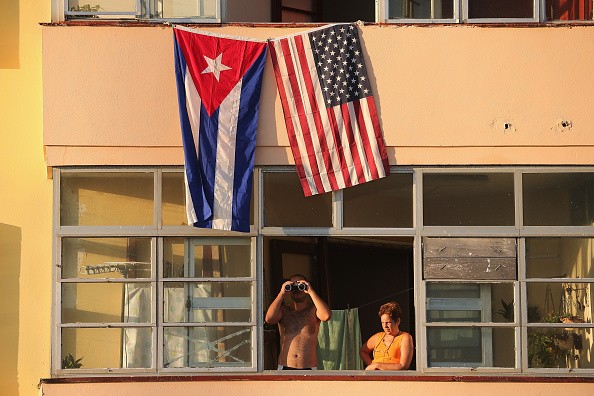 Cubans look out their window across the street from the newly reopened U.S. Embassy in hopes of watching the flag-raising ceremony in Havana, Cuba, Aug. 14, 2015.