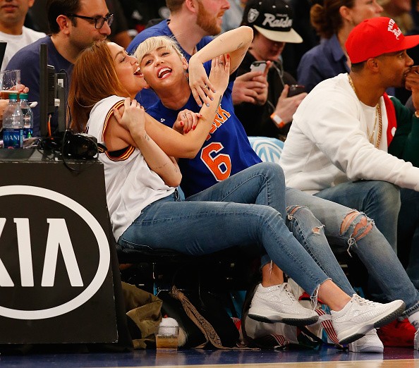 Miley Cyrus looks on with her sister Brandi during the game between the New York Knicks and the Cleveland Cavaliers at Madison Square Garden on March 26, 2016 in New York City.