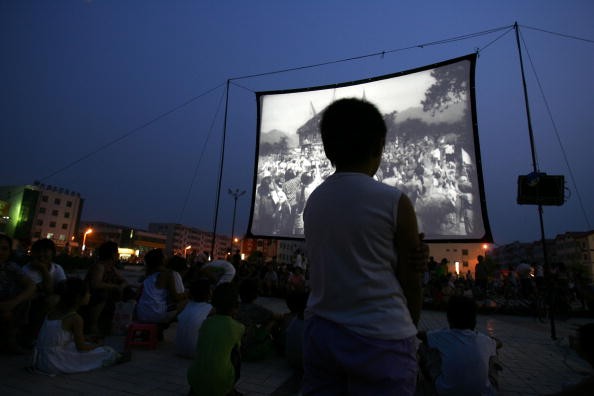 People watch a free movie at an open-air cinema at a square after an earthquake in Wen'an County, Hebei Province of China on July 4, 2006.