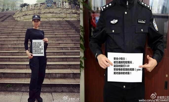 Perhaps the paper will be colored--or bigger--next time? Two police officers from Yibin in Sichuan Province pose for picture together with an important public message.
