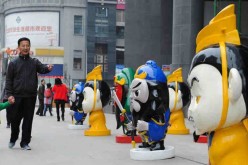 Locals walk by the cartoon figures of the Three Kingdoms period (AD 220-280) in front of a shopping mall in downtown Zunyi, Southwest China's Guizhou province, on April 1, 2016. 