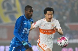 JIangsu Suning midfielder Ramires (L) competes for the ball against Shandong Luneng's Hao Junmin.