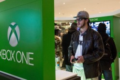 A man plays an XBox One while waiting in line to buy a unit of the game console from a Microsoft store. 