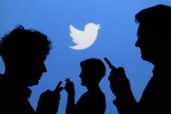 Twitter Logo is Seen Behind Silhouettes of People Using Smartphones