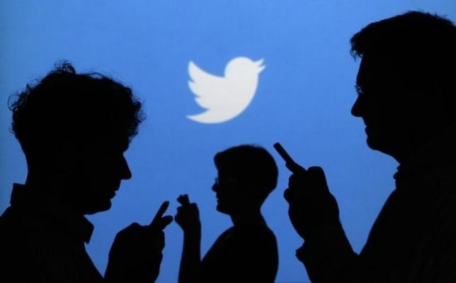 Twitter Logo is Seen Behind Silhouettes of People Using Smartphones
