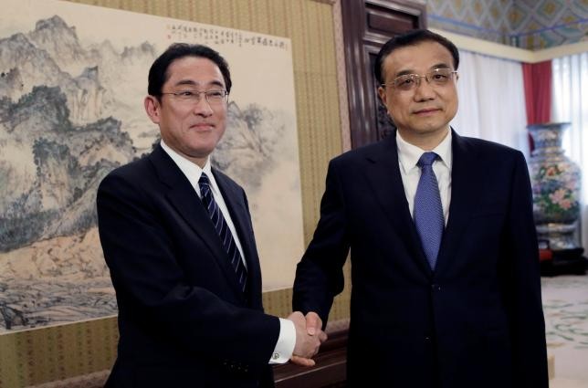 Japanese Foreign Minister Fumio Kishida poses with Chinese Premier Li Keqiang during their meeting in Beijing on Saturday, April 30.