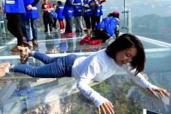 A female tourist lie on the glass sightseeing platform.